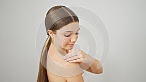 Young beautiful girl smiling confident applying skin lotion on shoulder over isolated white background