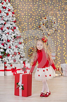 Young beautiful girl smiling, sitting near huge golden mirror plenty presents on fur Christmas green white luxury tree decorations