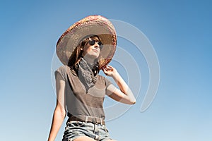 Young beautiful girl in sombrero and bandana dressed up as bandit of gangster. Female person in traditional mexican hat posing as