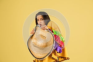 Young beautiful girl with sombrero isolated over yellow background.