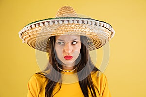 Young beautiful girl in sombrero isolated over yellow background. photo