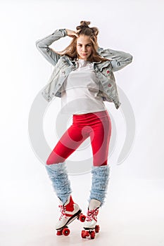 Young beautiful girl in sporty stylish clothes with long hair on four-wheeled rollers isolated on background