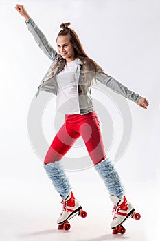 Young beautiful girl in sporty stylish clothes with long hair on four-wheeled rollers isolated on background