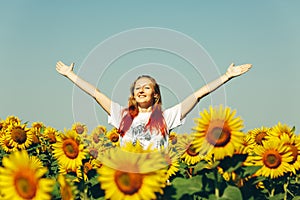 Young Beautiful Girl Standing In Sunflowers And Raising Hands Up. Freedom Lifestyle Outdoor Concept