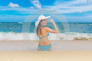 Young beautiful girl in a straw white hat back to the viewer on