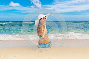 Young beautiful girl in a straw white hat back to the viewer on