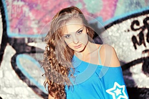 Young beautiful girl at the street with graffiti wall.