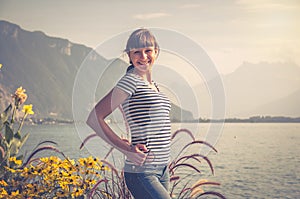 Young beautiful girl with striped shirt and jeans posing and smile on embankment of Lake Leman Geneva