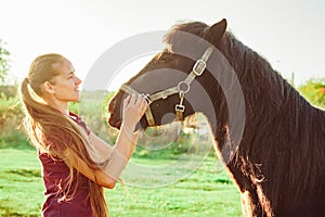 Young beautiful girl strokes horse