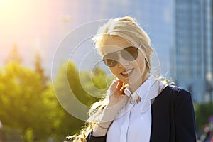 Young beautiful girl in sunglasses posing in the background of a building in the city