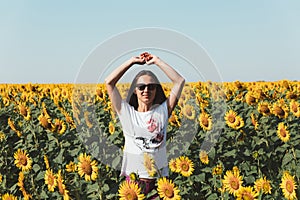 Young Beautiful Girl Standing In Sunflowers And Raising Hands Up. Freedom Lifestyle Journey Concept