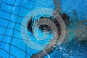 Young beautiful girl swimming under water in the swimming-pool with blue water