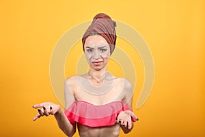 Young girl with towel on her head over isolated orange background shows emotions