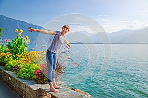 Young beautiful girl traveler with striped shirt and jeans posing and smile on embankment of Lake Leman Geneva