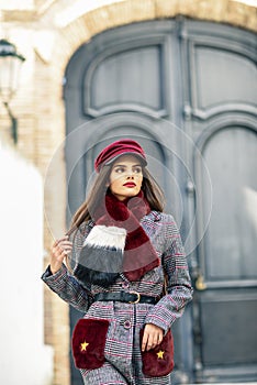 Young beautiful girl with very long hair looking away wearing winter coat and cap outdoors.