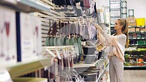 A young beautiful girl walks and examines the goods in the household department of the supermarket. Products for the