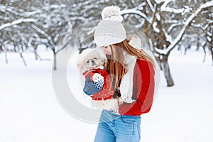 Young beautiful girl in a warm winter clothes plays with a puppy