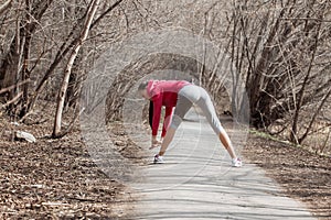 Young beautiful girl warming up before a jog in the Park