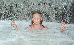 Young beautiful girl in waterfall relax under flowing water stream