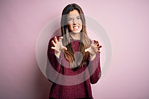 Young beautiful girl wearing casual sweater over isolated pink background smiling funny doing claw gesture as cat, aggressive and