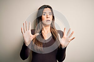 Young beautiful girl wearing casual sweater standing over isolated white background afraid and terrified with fear expression stop
