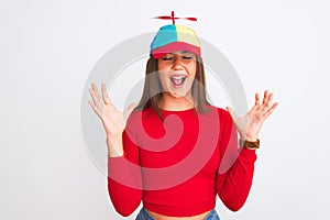 Young beautiful girl wearing fanny cap with propeller standing over isolated white background celebrating mad and crazy for