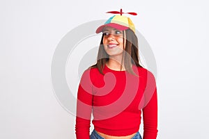 Young beautiful girl wearing fanny cap with propeller standing over isolated white background looking away to side with smile on