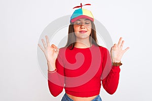 Young beautiful girl wearing fanny cap with propeller standing over isolated white background relax and smiling with eyes closed