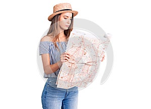 Young beautiful girl wearing hat holding city map thinking attitude and sober expression looking self confident
