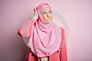 Young beautiful girl wearing muslim hijab standing over  pink background confuse and wondering about question