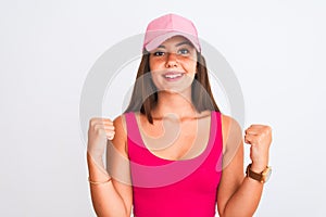 Young beautiful girl wearing pink casual t-shirt and cap over isolated white background celebrating surprised and amazed for