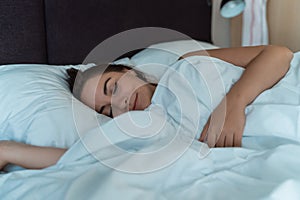 Young beautiful girl or woman sleeping alone in big bed at night