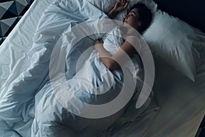 Young beautiful girl or woman sleeping alone in big bed at night, top view