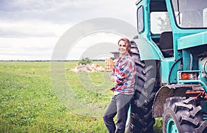 Young beautiful girl working on a tractor in the field, unusual work for women, a gender equality concept