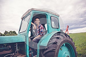 Young beautiful girl working on tractor in the field, unusual work for women, gender equality concept