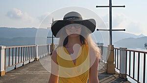 A young beautiful girl in a yellow dress walks along the pier. Sea. Ocean.