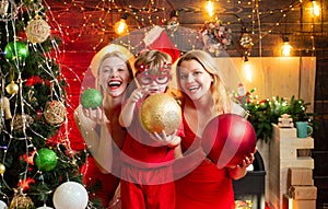 Young beautiful Girls and small little kid by the Christmas tree are looking at the camera.Ready to the party. Christmas