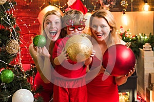 Young beautiful Girls and small little kid by the Christmas tree.Two Christmas girls are wearing red dresses on the