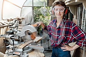Young beautiful handy professional happy female strong carpenter portrait wearing protective goggles working in carpentry diy