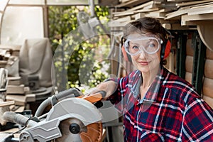 Young beautiful handy professional happy female strong carpenter portrait wearing protective goggles working in carpentry diy