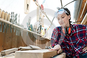 Young beautiful handy professional happy female strong carpenter portrait wearing protective goggles working in carpentry diy