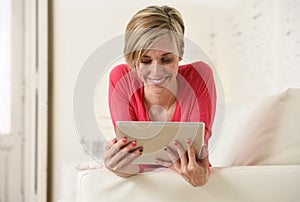 Young beautiful happy 30s woman smiling using digital tablet pad at home living room couch