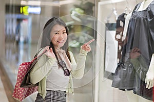 Young beautiful and happy Asian buying at shopping mall - young attractive and stylish Chinese woman holding shopping bags at