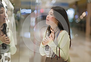 Young beautiful and happy Asian buying at shopping mall - young attractive and stylish Chinese woman holding shopping bags at