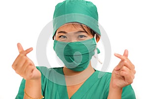 Young beautiful and happy Asian Chinese medicine doctor woman or hospital nurse in medical hat face mask and scrub doing fingers