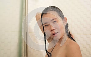 Young beautiful and happy Asian Chinese woman taking a shower in the bathroom washing her hair enjoying morning hygiene in