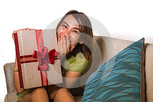 Young beautiful and happy Asian Indonesian woman holding birthday or Christmas present showing the gift box cheerful and excited