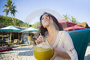 Young beautiful and happy Asian Korean or Chinese woman 20s drinking relaxed coconut juice on tropical paradise beach resort in su