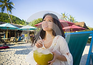 Young beautiful and happy Asian Korean or Chinese woman 20s drinking relaxed coconut juice on tropical paradise beach resort in su