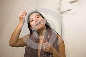 Young beautiful and happy Asian Korean woman applying serum facial skin care and face treatment in the bathroom enjoying morning photo